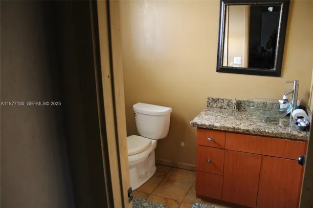 a bathroom with a granite countertop toilet and sink