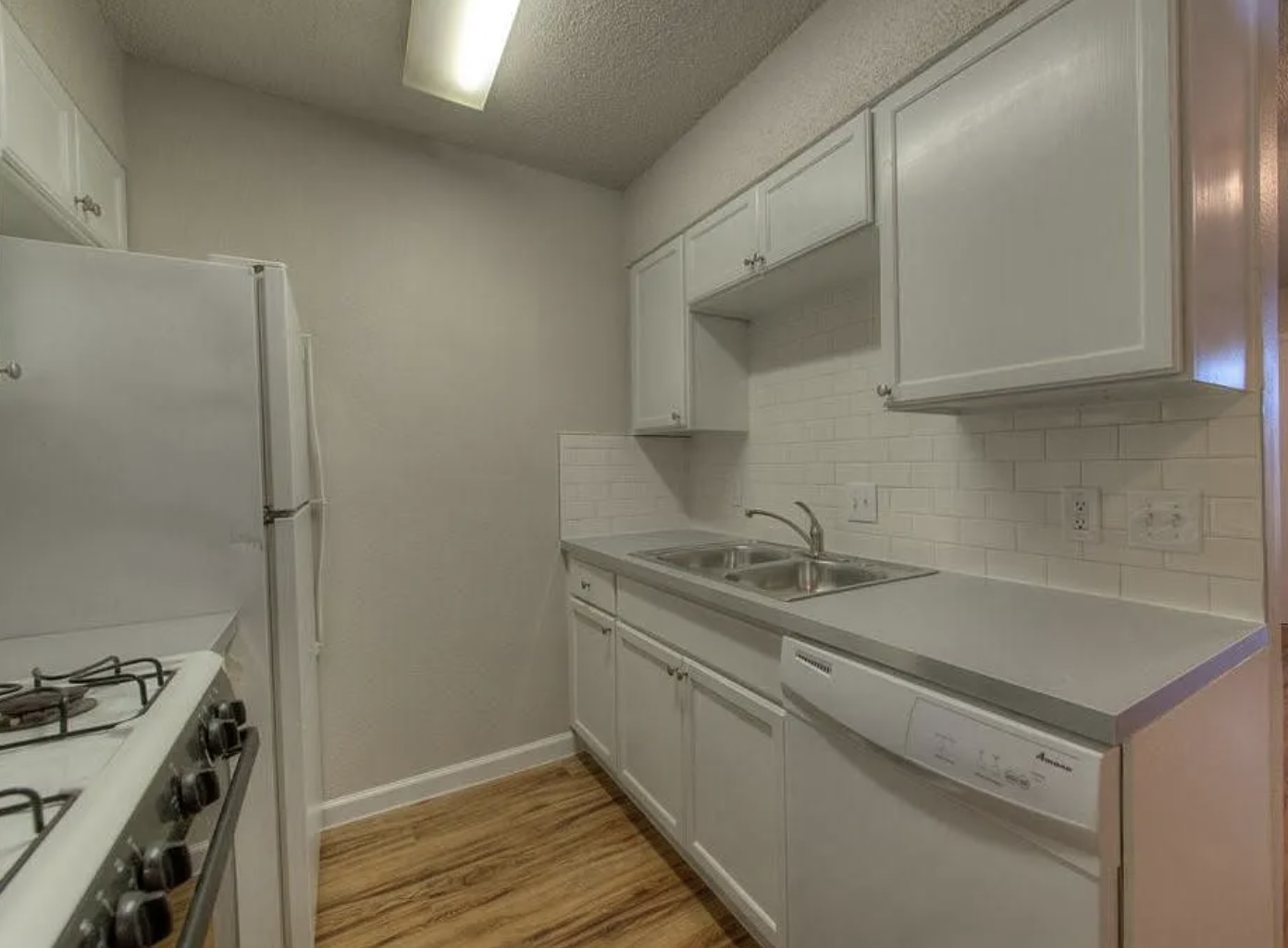 1124 Gardner Road, Unit B Austin, TX 78721 - Photo 8 of 15 Kitchen with white cabinets, white dishwasher, light wood finished floors, gas stove, and a textured ceiling