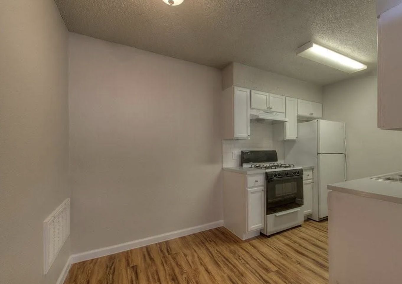 1124 Gardner Road, Unit B Austin, TX 78721 - Photo 9 of 15 Kitchen with white cabinetry, gas range, a textured ceiling, light countertops, and light wood-style floors