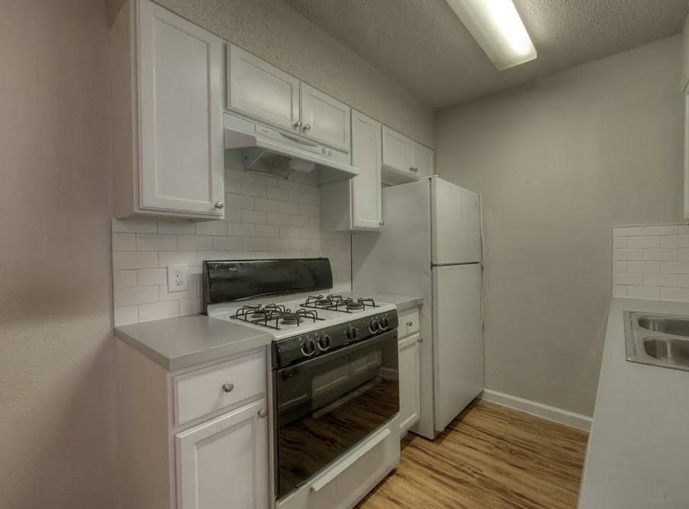 1124 Gardner Road, Unit B Austin, TX 78721 - Photo 10 of 15 Kitchen featuring gas range oven, white cabinetry, light countertops, light wood-style floors, and decorative backsplash