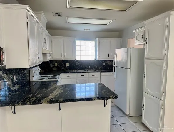 a kitchen with granite countertop a refrigerator and a stove