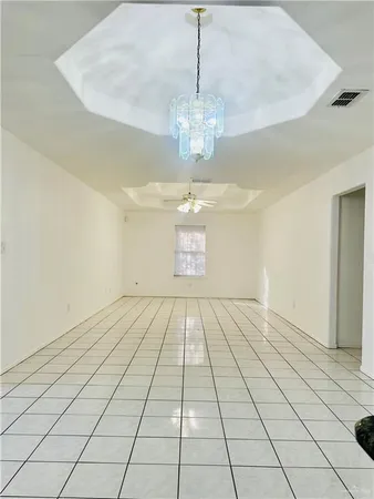 a view of an empty room with window and chandelier