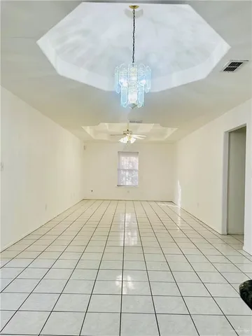 a view of an empty room with window and chandelier