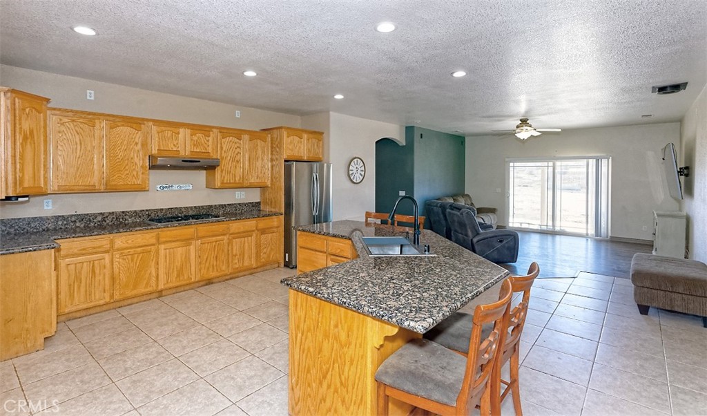 8855 Smith Road Phelan, CA 92371 - Photo 7 of 43 a kitchen with stainless steel appliances granite countertop wooden cabinets a sink dishwasher a dining table and chairs with wooden floor