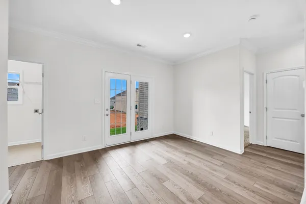 a view of an empty room with wooden floor and closet