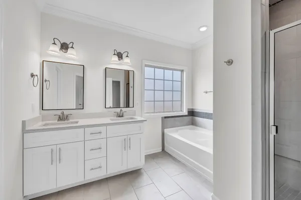 a bathroom with a double vanity sink a large mirror a bathtub and window
