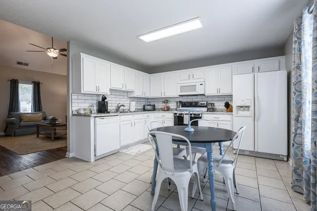 a kitchen with stainless steel appliances granite countertop a white cabinets and a refrigerator a stove top oven