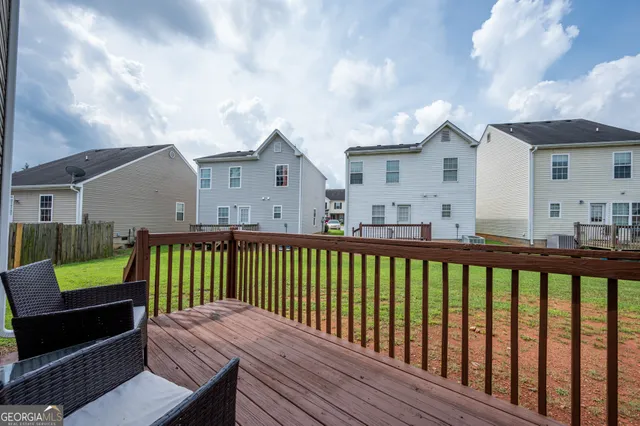 a view of a wooden chairs and a small deck in front of the house