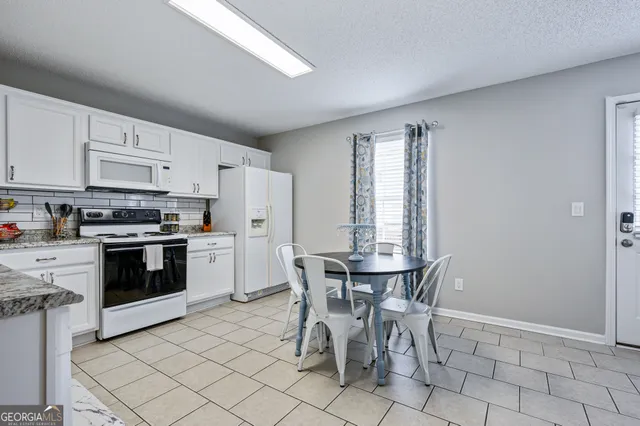 a kitchen with stainless steel appliances a white table and chairs in it
