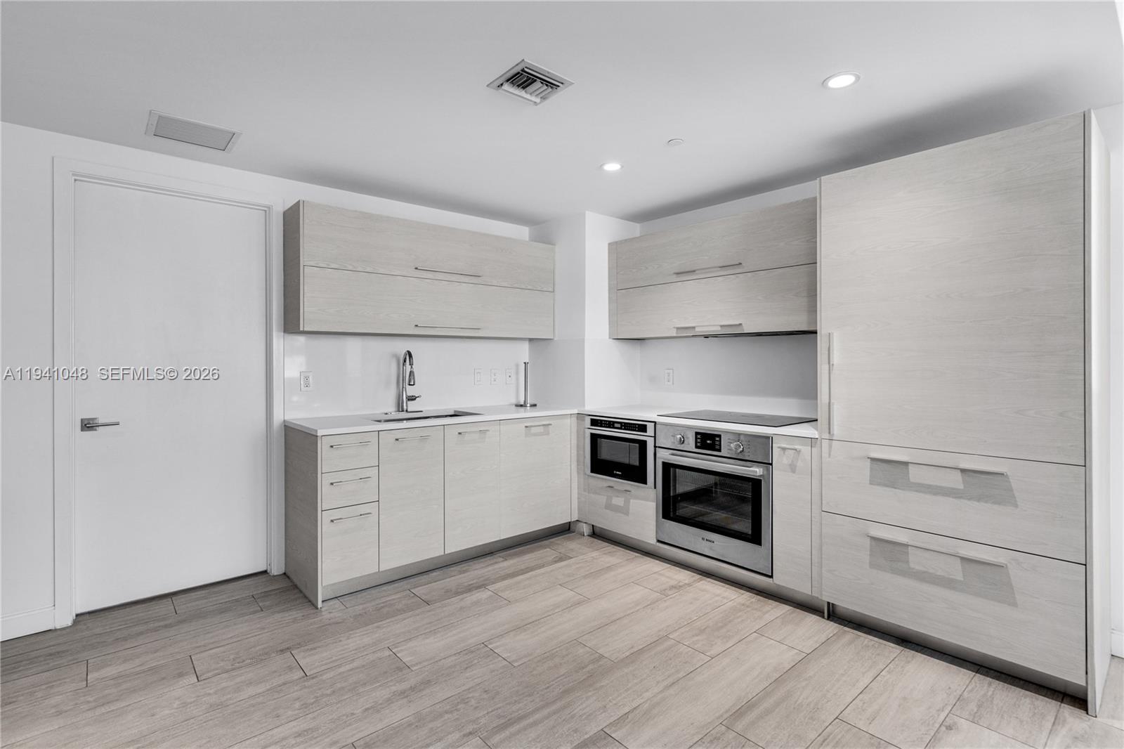 45 Southwest 9th Street, Unit 1001 Miami, FL 33130 - Photo 12 of 40 a kitchen with a sink stove and cabinets