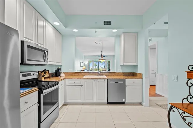 a large white kitchen with stainless steel appliances granite countertop a stove and a sink