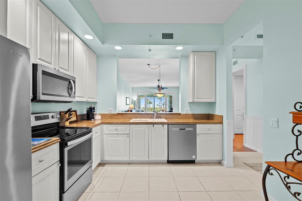 23 Harbour Isle Drive West, Unit 102 Fort Pierce, FL 34949 - Photo 12 of 40 a large white kitchen with stainless steel appliances granite countertop a stove and a sink