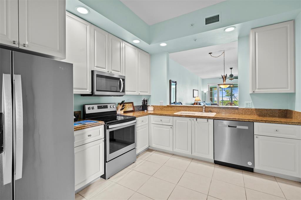 23 Harbour Isle Drive West, Unit 102 Fort Pierce, FL 34949 - Photo 13 of 40 a kitchen with white cabinets stainless steel appliances and a sink