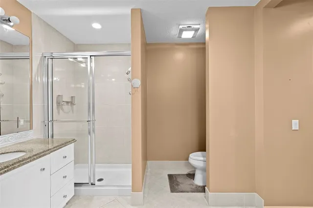 a bathroom with a granite countertop sink a toilet and shower