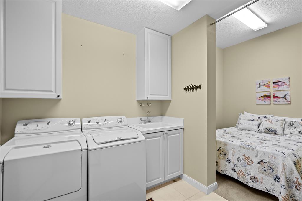 23 Harbour Isle Drive West, Unit 102 Fort Pierce, FL 34949 - Photo 25 of 40 a bedroom with a bed and a washing machine in it