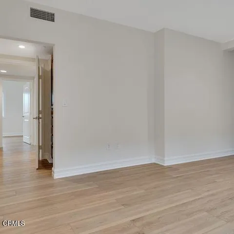 a view of an empty room with wooden floor and a bathroom