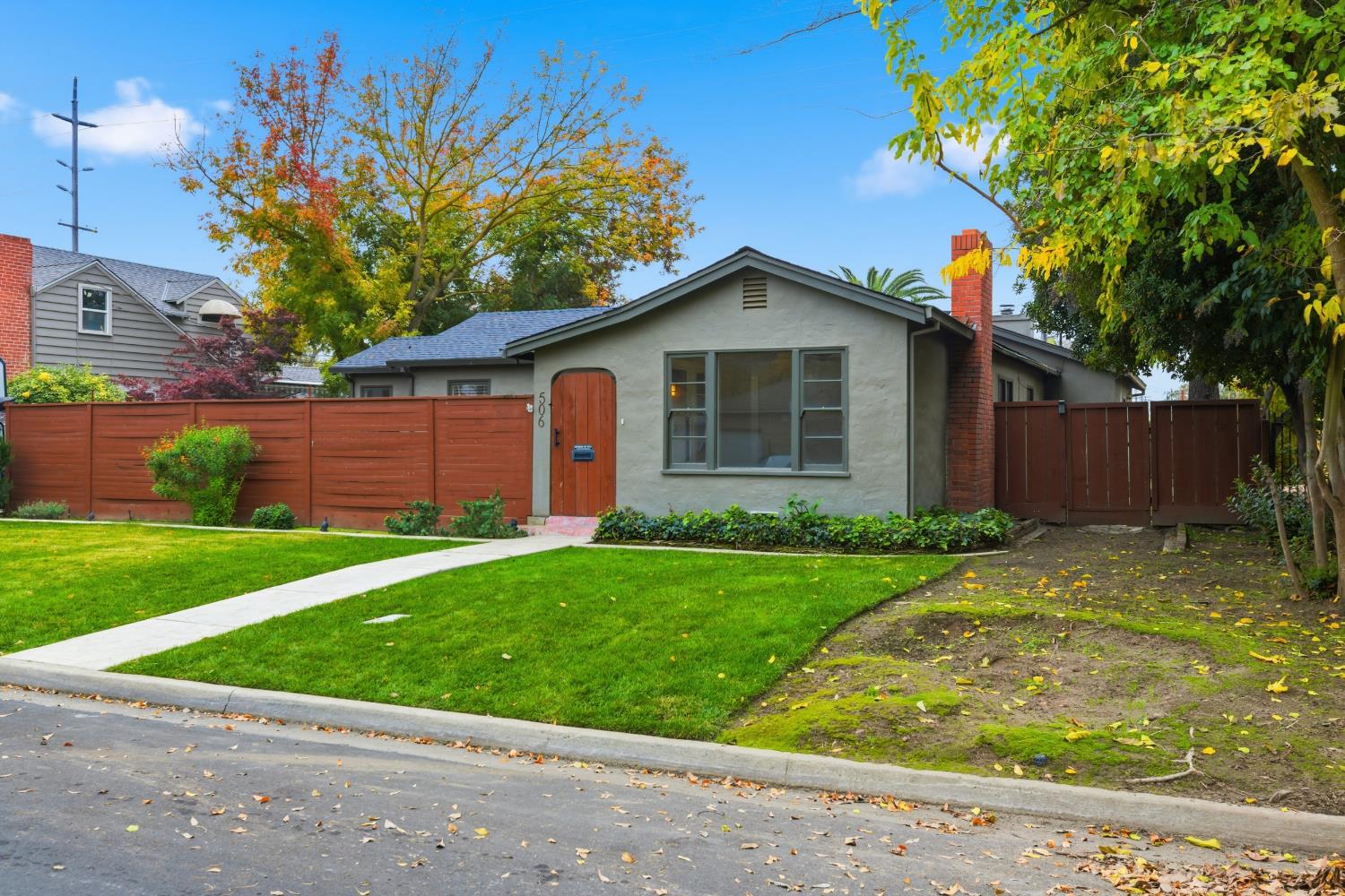 a view of a yard in front of a house with plants and large tree