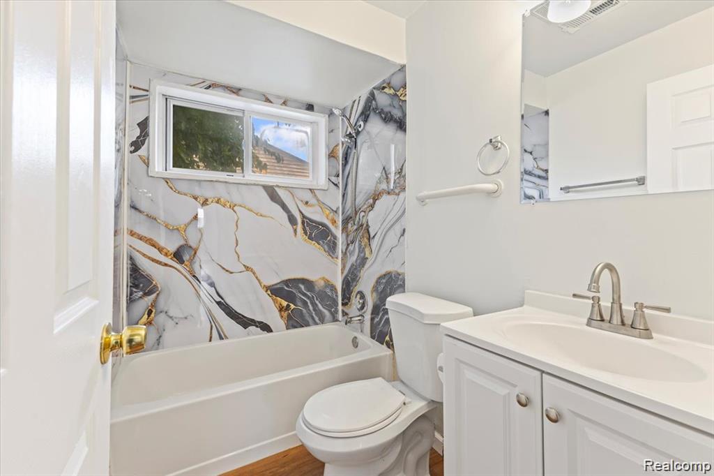 3930 Bayhan Street Inkster, MI 48141 - Photo 7 of 14 Bathroom featuring a tub and shower combination with a decorative wall surround, a single window, and a white vanity with a rectangular sink and brushed nickel faucet
