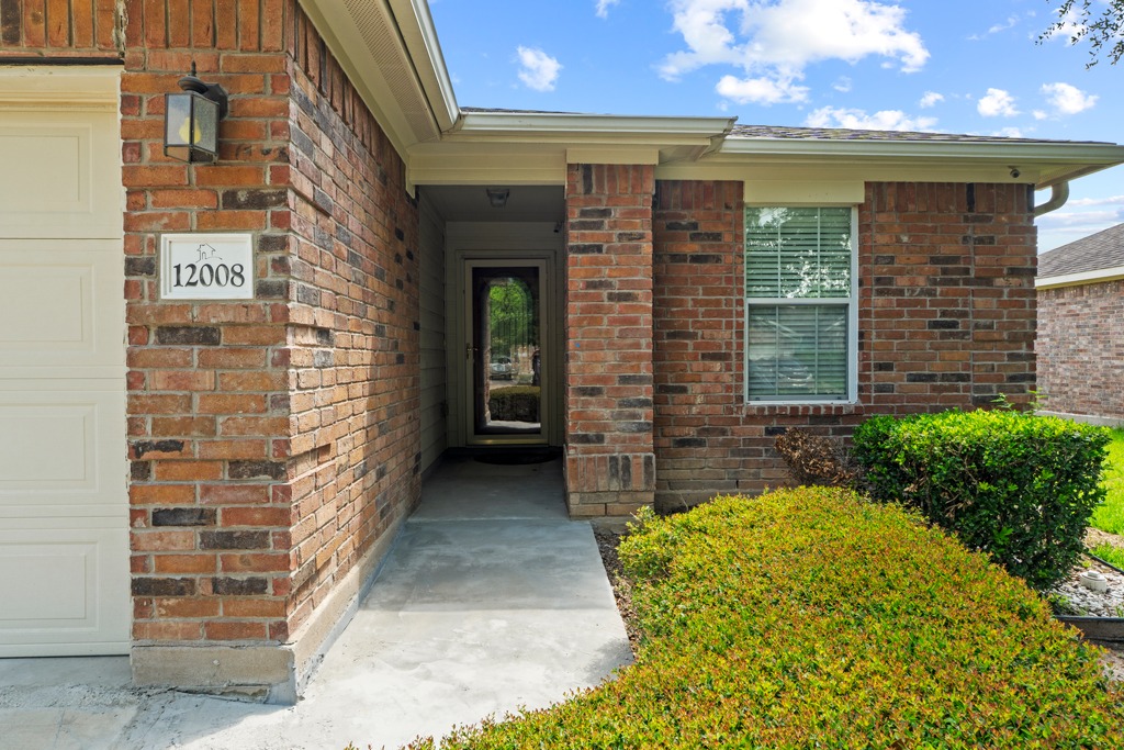 12008 Lansdowne Road Austin, TX 78754 - Photo 4 of 29 An inviting brick facade welcomes you home, framed by established shrubbery and a clean walkway.