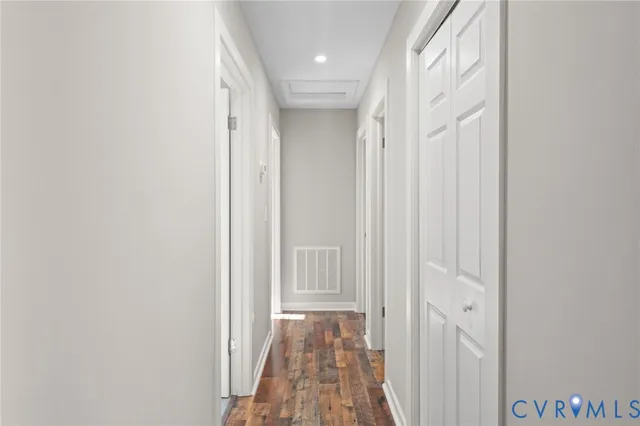 a view of a hallway with wooden floor and a bathroom