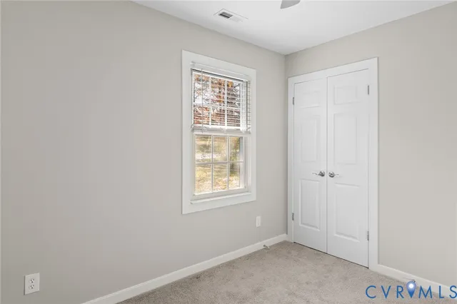 a view of an empty room with closet and a window