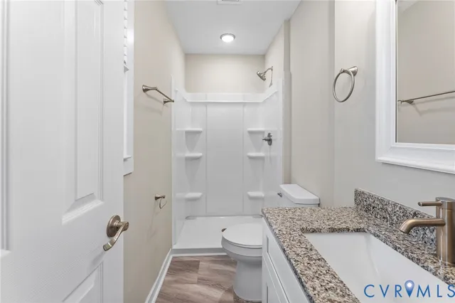 a bathroom with a granite countertop sink a toilet and shower