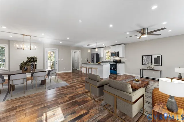 a living room with furniture kitchen view and a wooden floor