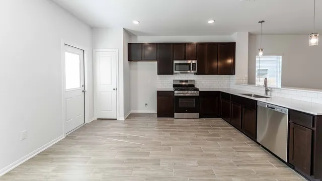 a large kitchen with stainless steel appliances granite countertop a sink counter space and cabinets