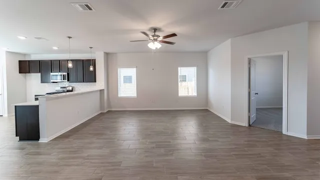 a view of an empty room with window and wooden floor