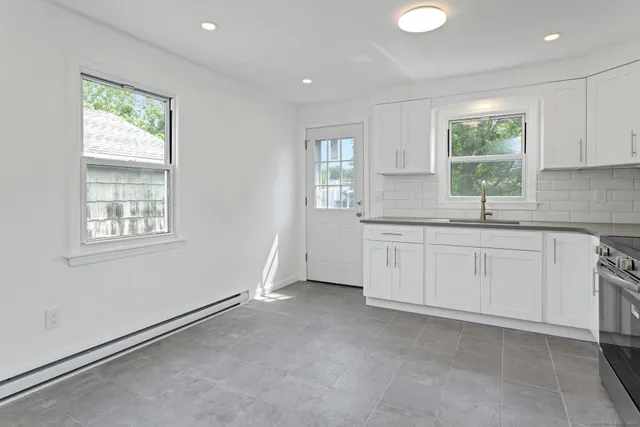 a kitchen with white cabinets and window