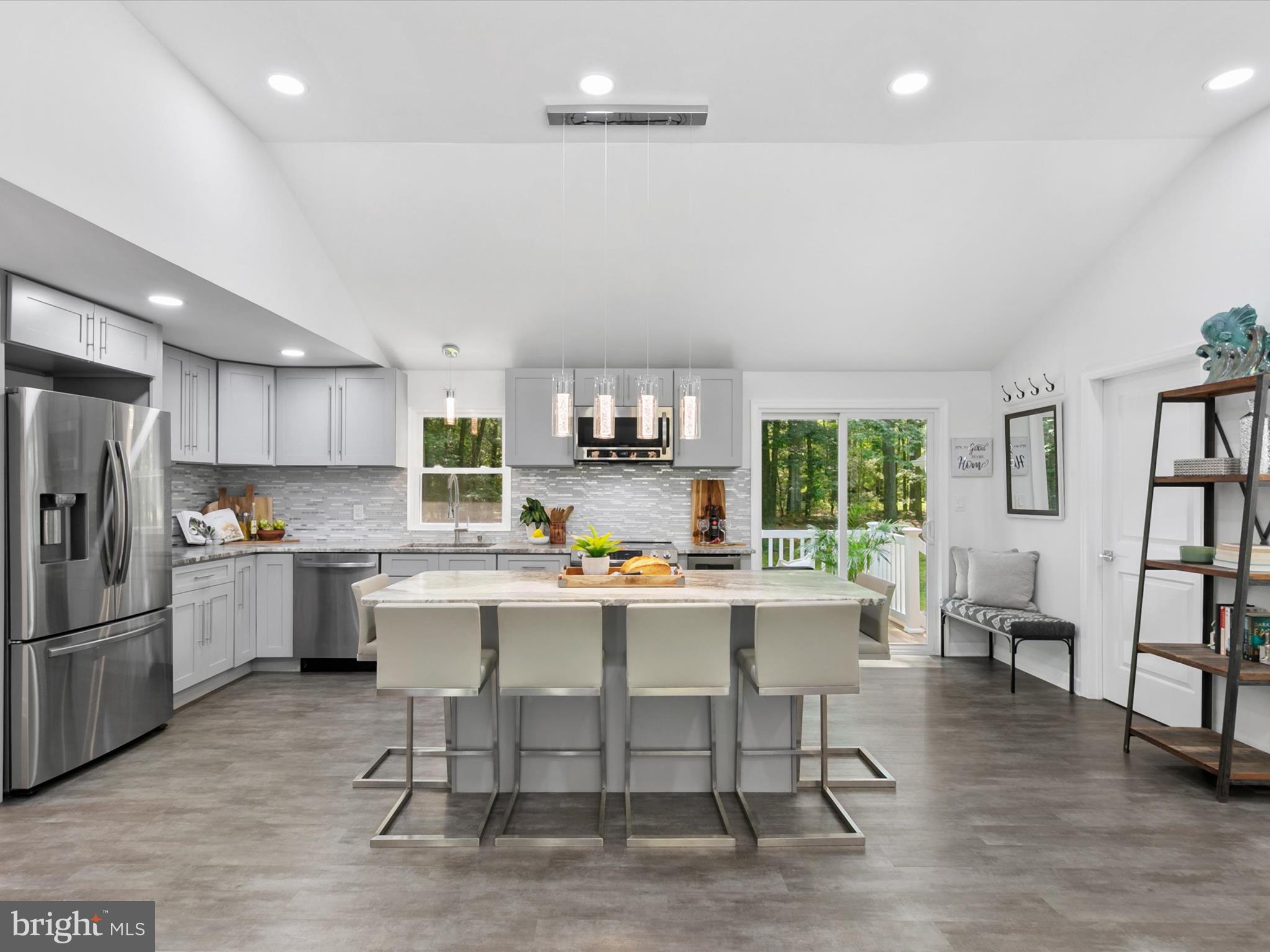 26076 Anderson Corner Road Georgetown, DE 19947 - Photo 7 of 36 a kitchen with a dining table chairs refrigerator and cabinets