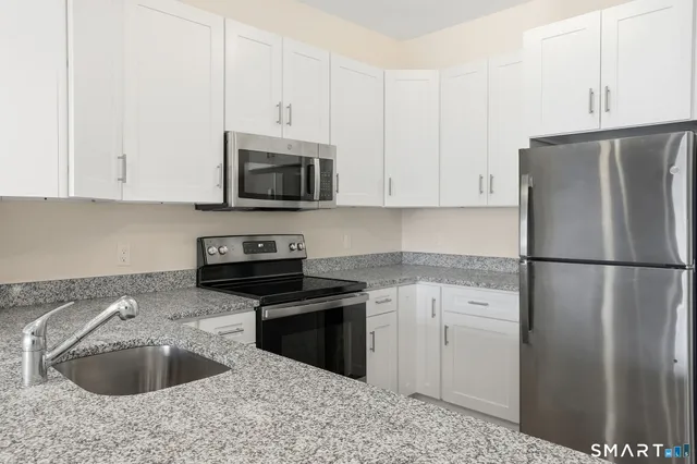 a kitchen with granite countertop a refrigerator sink and stove