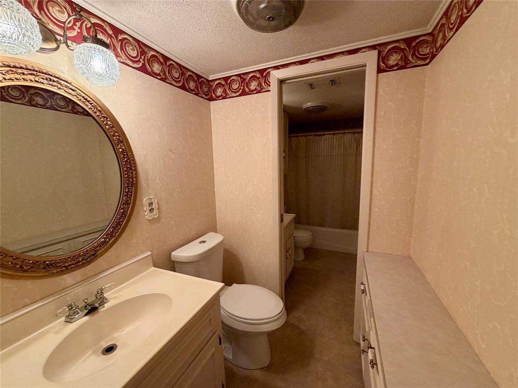 2030 Sycamore Street Paris, TX 75460 - Photo 15 of 24 Bathroom featuring a vanity with an integrated sink, a toilet, an ornate round mirror, and a wall-mounted light fixture