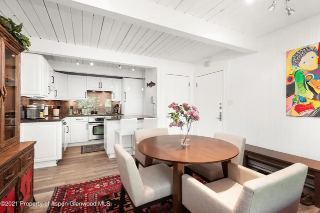 a kitchen with stainless steel appliances kitchen island granite countertop a dining table chairs and a refrigerator