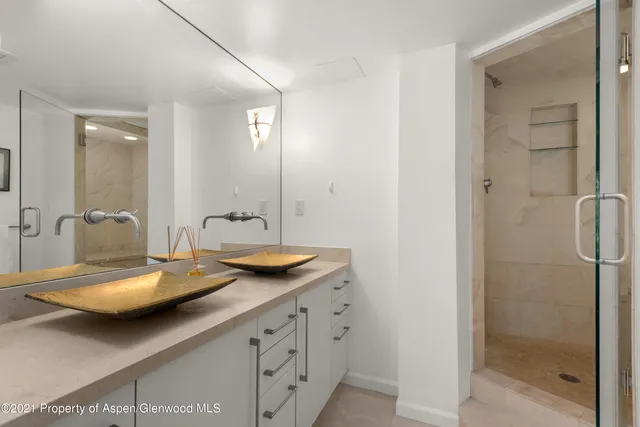 a bathroom with a double vanity sink and mirror with shower