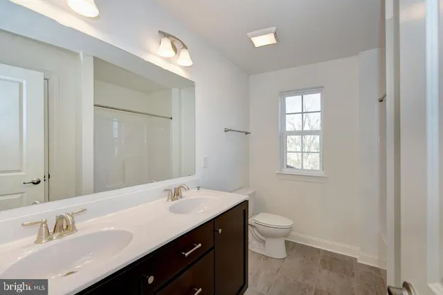 a spacious bathroom with a double vanity sink a toilet and a window