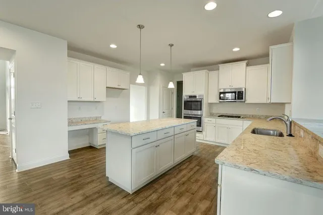 a large kitchen with stainless steel appliances granite countertop a sink a stove and a refrigerator