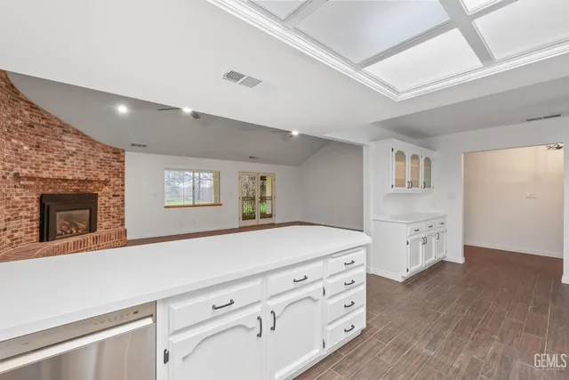 an empty room with wooden floor a ceiling fan a fireplace and windows
