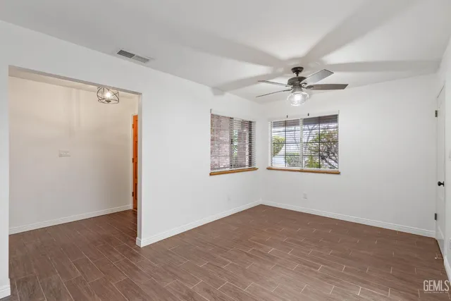 a view of an empty room with a window and wooden floor