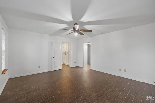 an empty room with wooden floor chandelier fan and windows