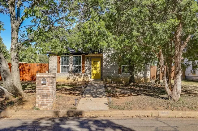 a front view of a house with a tree