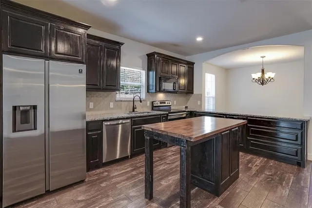 a kitchen with granite countertop a sink stove and refrigerator