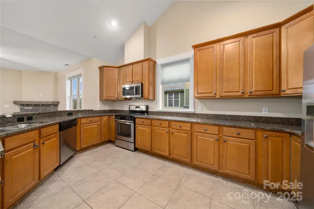 a large kitchen with stainless steel appliances granite countertop a stove sink and cabinets