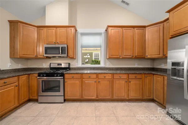 a kitchen with stainless steel appliances granite countertop a stove top oven a sink dishwasher and a microwave oven on the blue kitchen countertops