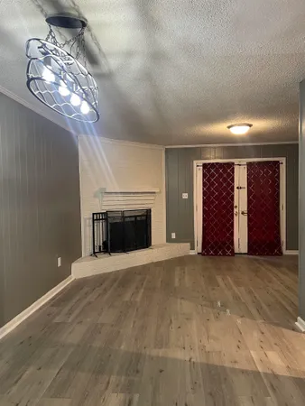 an empty room with windows fireplace and chandelier