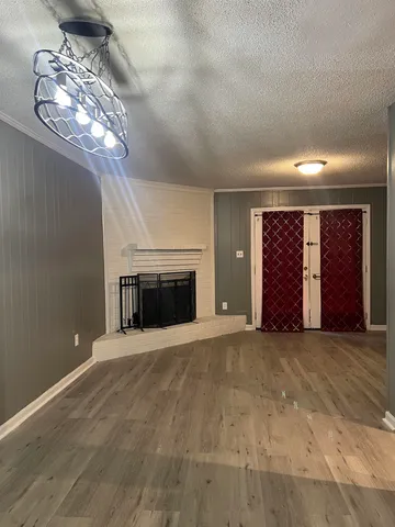 an empty room with windows fireplace and chandelier