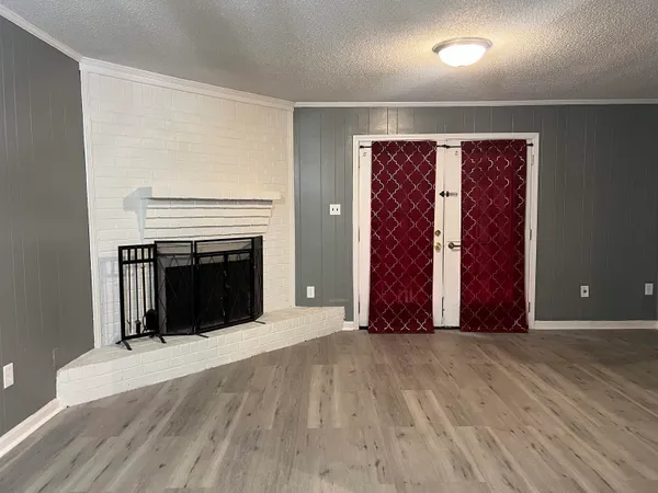 an entryway and an empty room with wooden floor
