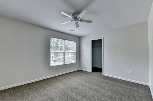 an empty room with a ceiling fan and window