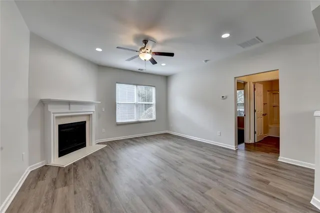 an empty room with wooden floor fireplace and windows