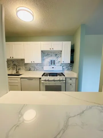 a kitchen with kitchen island granite countertop a sink and a stove top oven
